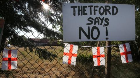 A sign attached to the camp fence says, “Thetford Says No!” at RAF Barnham on August 7, 2026, in Thetford, UK. A protest camp has been set up by locals who oppose the use of RAF Barnham as a site for 1,250 asylum seekers. (Getty Images)