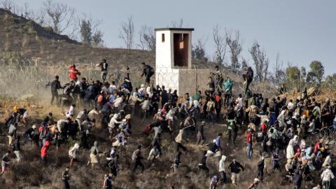 Migrants storm a barbed-wire fence as they attempt to cross the land border with Spain's African enclave of Ceuta near Fnideq in northern Morocco on September 15, 2024. (Photo by AFP) (Photo by -/AFP via Getty Images)