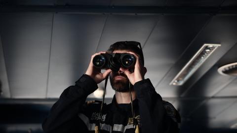 A member of the French Navy observes through his binoculars from the command post before the departure of an amphibious helicopter carrier in Toulon on February 17, 2026. (Getty Images)