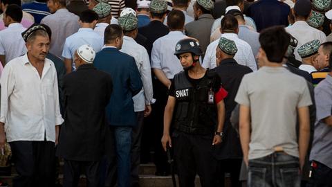 A policeman standing guard as Muslims arrive for the Eid al-Fitr morning prayer at the Id Kah Mosque in Kashgar in China's Xinjiang Uighur Autonomous Region (JOHANNES EISELE/AFP/Getty Images)