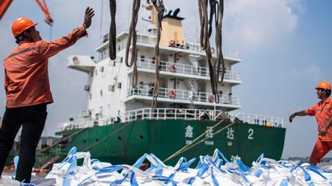 Workers unloading bags of chemicals at a port in Zhangjiagang in China's eastern Jiangsu province, August 7, 2018