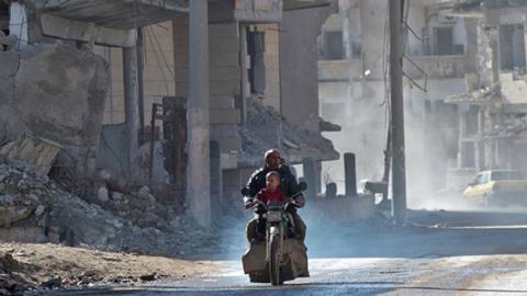 A Syrian man and a child ride a motorcycle in the Islamic State (IS) group's former Syrian capital of Raqa in northern Syria.