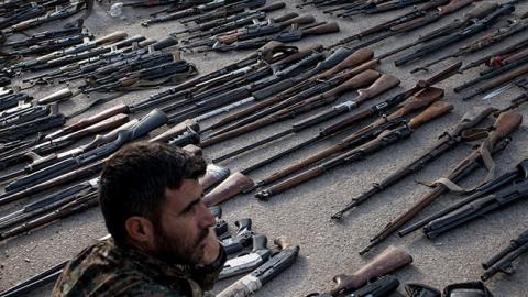 An Syrian Democratic Forces (SDF) fighter looks over seized ISIL weapons that were found in the last stronghold of the extremist group as they were displayed at an SDF base outside Al Mayadin, Syria.