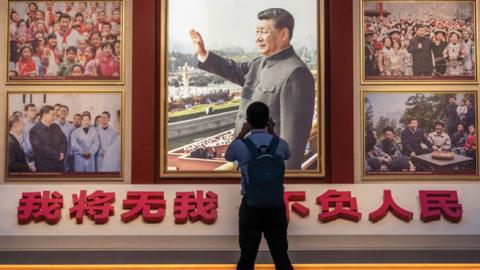 A man takes a photo of a wall showing images of Communist Party Chairman and President Xi Jinping as part of a display at the newly built Museum of the Communist Party of China on June 25, 2021, in Beijing, China. (Getty Images)