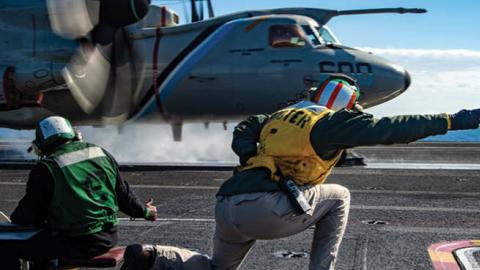 Lt. Lisa Amble signals to the pilot of an E-2D Hawkeye before launching from the flight deck of the Nimitz-class aircraft carrier USS Harry S. Truman (CVN 75), Feb. 21, 2022. (U.S. Navy photo)