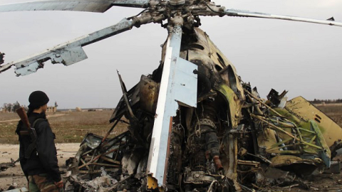 Rebel fighters inspecting the wreckage of a Syrian army helicopter after Islamic State of Iraq and the Levant (ISIL)'s fighters allegedly destroyed it when they left the Meng Military Airport, Aleppo, March 1, 2014 (MOHAMMED AL-KHATIEB/AFP/Getty Images)