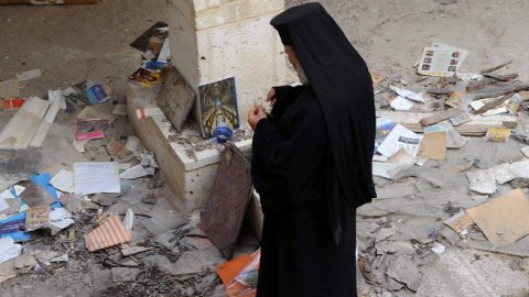 A Christian priest inspects the damages inside a church in the ancient Christian town of Maalula, northeast of Damascus on April 14, 2014 AFP/Getty Images)