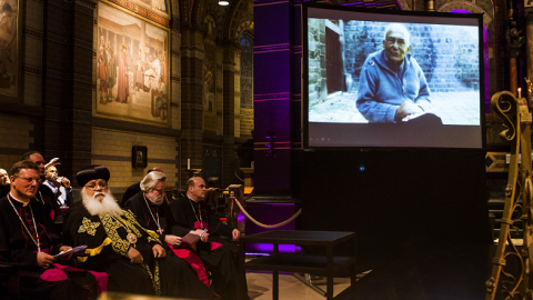 Clerics sit next to a screen showing Dutch priest Frans van der Lugt during a remembrance ceremony for the dead priest in the Sint Nicolaasbasiliek in Amsterdam, on April 11, 2014. (REMKO DE WAAL/AFP/Getty Images)