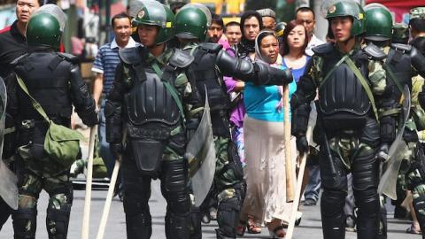Uighur people (C) walk near police as they form a line across a street on July 8, 2009 in Urumqi, China. (Guang Niu/Getty Images)