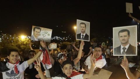Syrians hold pictures of re-elected Syrian President Bashar al-Assad in Damascus after Assad was announced as the winner of the country's presidential elections on June 4, 2014. (JOSEPH EID/AFP/Getty Images)