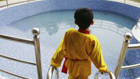 A young boy views a private swimming pool at a luxury residential area in Jiangmen, Guangdong Province, China, Febuary 15, 2005. (Cancan Chu/GettyImages)