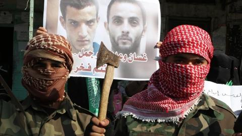 Palestinians celebrate an attack on a Jerusalem synagogue while standing in front of a poster of the attackers in the southern Gaza Strip on November 18, 2014. (SAID KHATIB/AFP/Getty Images)