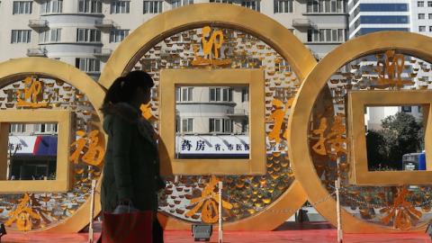 People walk past a copper coin-shapped decoration for Chinese New Year on January 20, 2014 in Zhengzhou, China. (ChinaFotoPress/ChinaFotoPress via Getty Images)