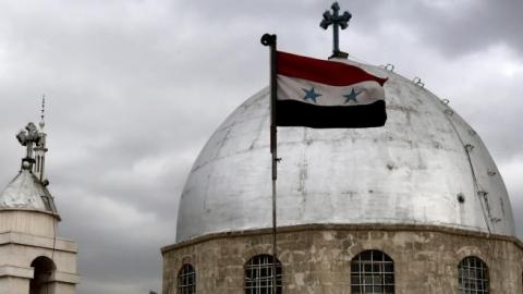 The Syrian flag flying in front of the dome of the Syrian Saint Sarkis Church for Armenian Orthodox in Damascus on January 6, 2015. (LOUAI BESHARA/AFP/Getty Images)