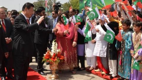 Chinese President Xi Jinping waves to Pakistani children as his Pakistani counterpart Mamnoon Hussain (L) and Pakistani Prime Minister Nawaz Sharif (C, back) look on, upon arrival at Islamabad airport in Islamabad, on April 20, 2015. (Photo by (Pakistan P