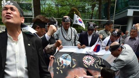 South Korean activists tear a banner showing a picture of Japan's Prime Minister Shinzo Abe during a protest outside the Japanese embassy in Seoul on April 28, 2015. (JUNG YEON-JE/AFP/Getty Images)
