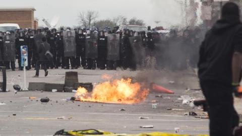 With Baltimore Police officers in riot gear lining the street, a man stands at the corner of Pennsylvania Avenue and North Avenue , April 27, 2015 in Baltimore, Maryland. (Drew Angerer/Getty Images)