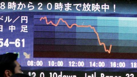 Business people watch an electric board indicating the foreign currency of 114.59-62 yen against the US dollar at a foreign exchange brokers on December 6, 2006 in Tokyo, Japan. (Junko Kimura/Getty Images)