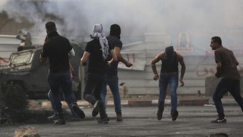 Palestinian protesters hurl rocks at an Israeli armoured vehicle (background) during clashes next to the Jewish settlement of Beit El, north of Ramallah on October 19, 2015. (ABBAS MOMANI/AFP/Getty Images)