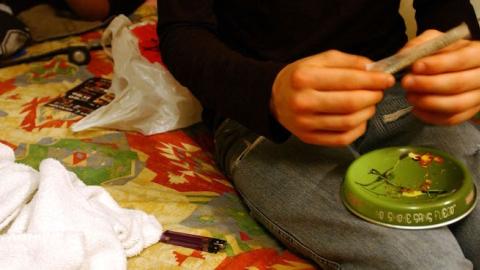 A student prepares a cigarette with tobacco and marijuana during a school trip, May 20, 2004. (Marco Di Lauro/Getty Images)