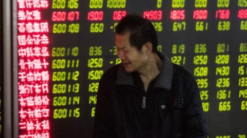 An investor looks at screens showing stock market movements at a securities company in Beijing on January 5, 2016. (FRED DUFOUR/AFP/Getty Images)
