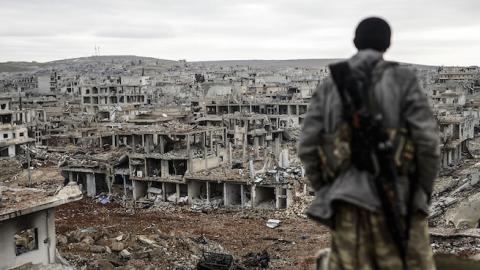 Musa, a 25-year-old Kurdish marksman, stands atop a building as he looks at the destroyed Syrian town of Kobane on January 30, 2015. (BULENT KILIC/AFP/Getty Images)