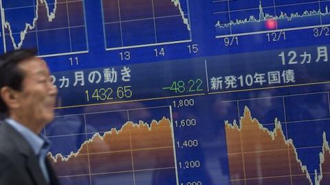 A man walks past a screen showing global stock market information on the street in Tokyo on August 25, 2015. (Chris McGrath/Getty Images)