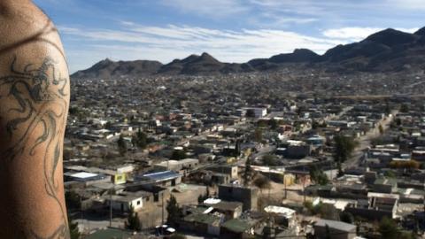 A young tattooed man stands on the hill overlooking the city of Juarez, Mexico. (Shaul Schwarz/Getty Images)