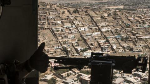 A U.S. Army advisor for the Afghan Air Force signals the Afghan crew chief during a training mission outside of Kabul, September 13, 2017 (Andrew Renneisen/Getty Images)