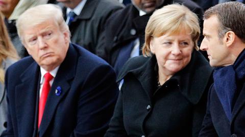 French President Emmanuel Macron Speaks to German Chancellor Angela Merkel as they sit next to US President Donald Trump and US First Lady Melania Trump in Paris on November 11, 2018 (Photo credit: FRANCOIS MORI/AFP/Getty Images)