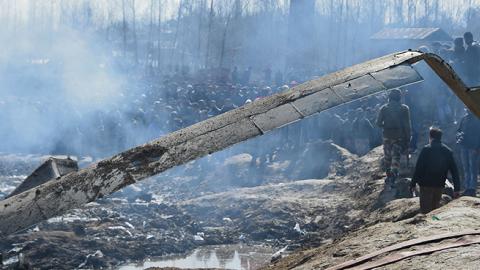 Indian soldiers and Kashmiri onlookers stand near the remains of an Indian Air Force helicopter after it crashed in Budgam district, outside Srinagar on February 27, 2019. (AUSEEF MUSTAFA/AFP/Getty Images)