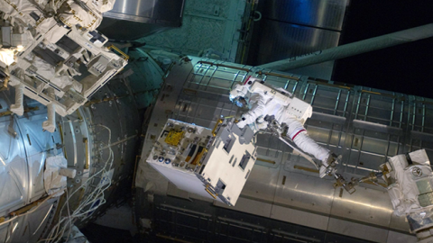 NASA astronaut Ronald Garan attached to the robotic arm Canadarm2 moves a failed ammonia pump module from a storage platform on the ISS to the cargo bay of the space shuttle Atlantis during a planned spacewalk July 12, 2011. (NASA via Getty Images)