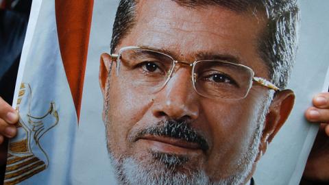 A protester holds a poster of Mohammed Morsi during a protest against the mass execution sentence of 529 supporters of Morsi and the Muslim Brotherhood on March 28, 2014. (Rahman Roslan/Getty Images)