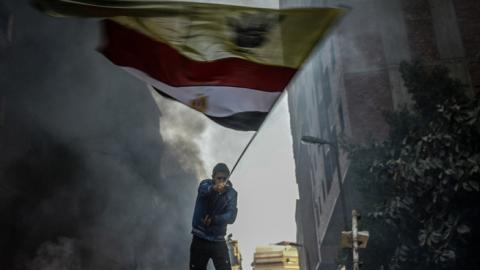 An Egyptian protester raises flags during the clashes between Egyptian police and protesters after declaring the Muslim Brotherhood as a terrorist group in Alf Maskan district of Cairo, Egypt, December 27, 2013. (Getty Images)