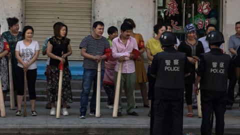 A mix of ethnic Uyghur and Han shopkeepers hold large wooden sticks as they are trained in security measures on June 27, 2017 next to the old town of Kashgar, in the far western Xinjiang province, China. (Kevin Frayer/Getty Images)