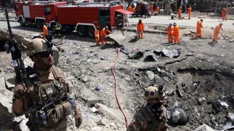 Afghan security forces walks as municipal workers gather to clean up near the crater from where a tractor packed with explosives exploded the night before at the Green Village in Kabul on September 3, 2019. (Getty Images)