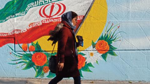 An Iranian woman walks past a mural painting of the Islamic republic's national flag in central Tehran on November 21, 2019.