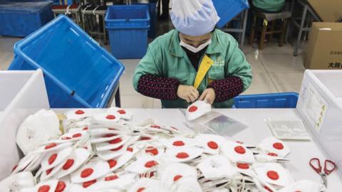An employee works on the assembly line to make protective masks at a factory in Shanghai, China, on Jan. 31.