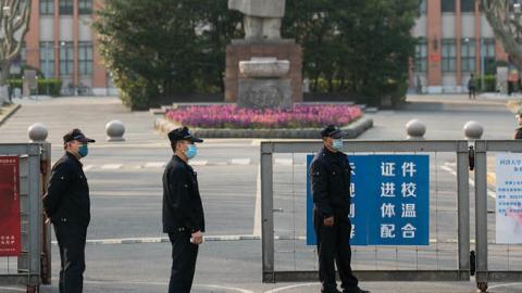  Security men wearing protective masks stand near a statue of former Chinese leader Mao Zedong at a gated entrance of Tongji University on March 17, 2020 in Shanghai, China.