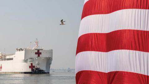 America flags are presented for the send of the U.S. Navy hospital ship USNS Comfort at Naval Air Station Norfolk Pier 8, Saturday, March 28, 2020, as she gets underway for New York City where she will support the city’s response to COVID-19. 