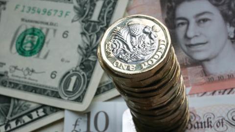 A stack of £1 coins is seen with the new £10 note alongside US dollar bills on October 13, 2017 in Bath, England