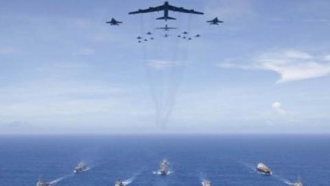 The aircraft carrier USS Ronald Reagan (CVN 76), foreground, leads a formation of Carrier Strike Group Five ships as Air Force B-52 Stratofortress aircraft and Navy F/A-18 Hornet aircraft pass overhead for a photo exercise during Valiant Shield 2018 in th