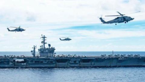 MH-60R Sea Hawks attached to Helicopter Maritime Strike Squadron HSM-77 (the “Saberhawks”) hover in formation between the aircraft carrier USS Ronald Reagan (foreground) and USS Nimitz while under way in the South China Sea, July 7, 2020. The Nimitz and R