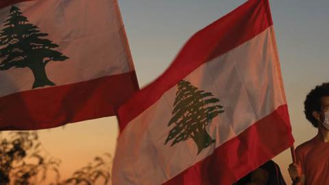 People wave Lebanese flags and chant to mark the one-year anniversary of anti-government protests on October 17, 2020 in Beirut, Lebanon.