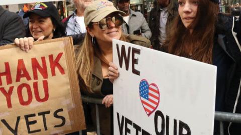 Pedestrians watch the 100th annual Veterans Day parade in New York, Nov. 11, 2019.