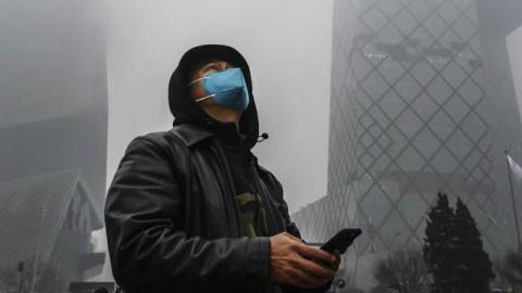 The CCTV building, shrouded in fog and pollution, during rush hour in Beijing.