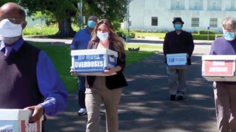 Volunteers carry boxes of signed petitions for a ballot measure decriminalizing a number of hard drugs in Salem, Ore., June 26.