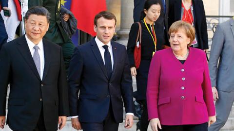 French President Emmanuel Macron accompanies Chinese President Xi Jinping and German Chancellor Angela Merkel after their meeting at the Élysée Presidential Palace on March 26, 2019 in Paris, France.