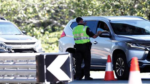 Police officer speaks to a motorists who is entering Queensland from New South Wales through the border checkpoint on December 21, 2020 in Coolangatta, Gold Coast, Australia