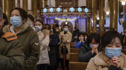 Chinese Christians pray and wait in line to take communion during a Christmas Mass at a Catholic Church on December 24, 2020 in Beijing, China